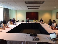 State Interagency Coordinating Council members in discussion, sit together at tables facing each other, in a U-shaped formation.