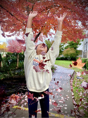 young girl smiling at colorful leaves falling down her face
