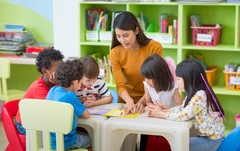 Teacher providing a lesson to young children. 