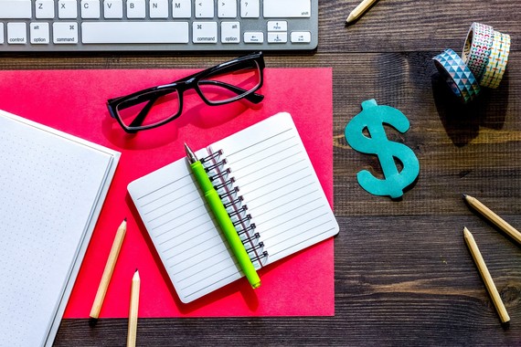 A desk covered in pencils, pens, notebooks, keyboard and other office materials. 