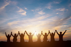 Group of individuals hold hands to the sky in triumph