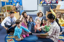 Early Learning class room setting with teacher reading to students