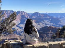 photo of a young girl sitting down looking out toward the grand canyon 