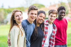 A group of youth smiling together outside. 