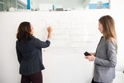 Two people in front of white board 