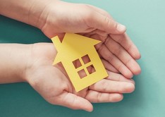 Hands holding a paper house