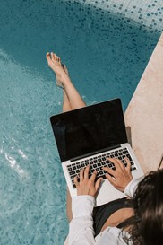 woman on lap top by pool