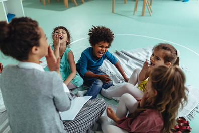 Children laughing with teacher in preschool setting