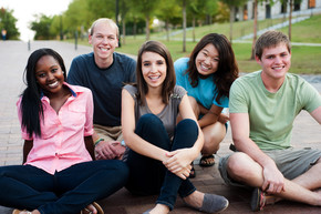 Young people sitting outside together smiling