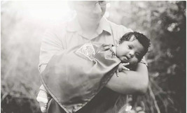 baby with down syndrome wearing a superhero cape with his dad