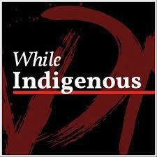 “While Indigenous” podcast logo, in white, seraph letters. “Indigenous” underlined in a red line, placed on maroon paint strokes and black background.