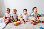 4 babies sitting down with different ethic backgrounds playing 