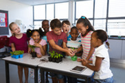 Diverse group of youth in classroom showing excitement with planting seeds