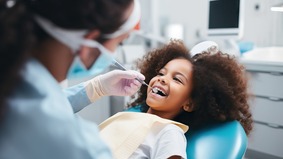 Young girl getting teeth examined by dentist. 