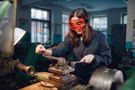 teen in jumper with goggles working on machinery 