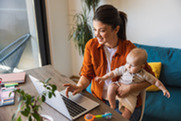 Woman working at computer with baby on her lap.