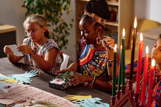 mom and two girls preparing for Kwanzaa by wrapping gifts and lighting candles