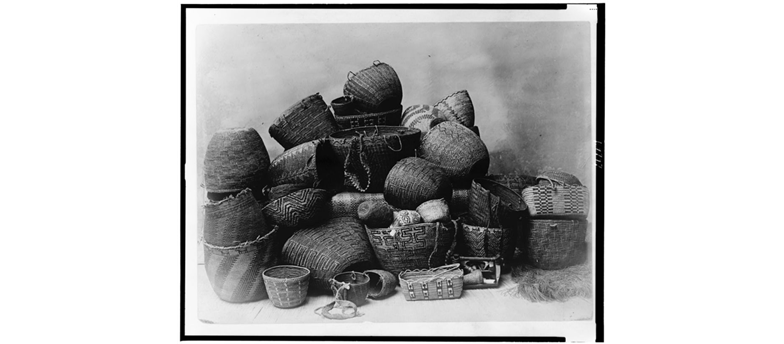 Black and white photo of a several intricately woven Puget Sound baskets, posed in a giant pile.