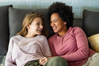 teen girl and adult woman sitting on couch and smiling at each other