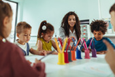 Photo of a teacher and kids around a table during craft time.