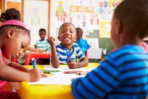 Black preschool age children, in a classroom, at a table using markers.