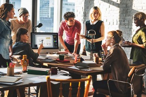 Group of people gathered around a computer discussing ideas