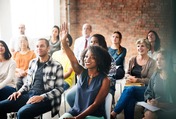 group of people sitting in chairs woman smiling raising hand