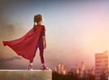 girl standing on roof with red superhero cape