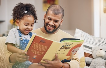 adult and child smiling reading a book together