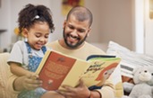 adult and child smiling reading a book together