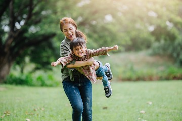 adult woman and toddler in a field smiling