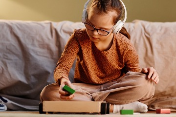 girl playing wtih blocks in her room with headphones