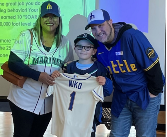 adults and child smiling at camera with Mariners baseball gear