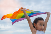 Young girl lifting unfurled Pride Month flag.