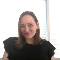 Photo of new ESIT Data Coordinator, Teanne Stangle, smiling at the camera, surrounded in a brightly lit background.