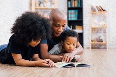 African American father reading a fairy tale fable story for kids at home. 