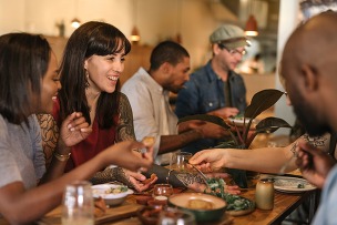 Smiling young friends enjoying dinner together in a trendy bistro