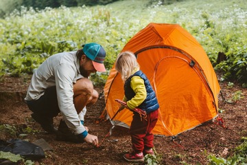Camping family vacations child helps father to set tent