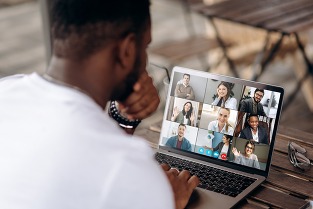 Person on video call with laptop in cafe