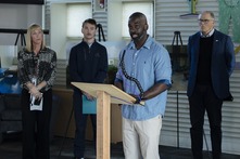 Background, left to right: Jennifer Redman, Bailey Smith, & Governor Jay Inslee. Speaking at the podium: Eugene Barkley.