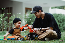 boy sitting with dad on grass blowing bubbles