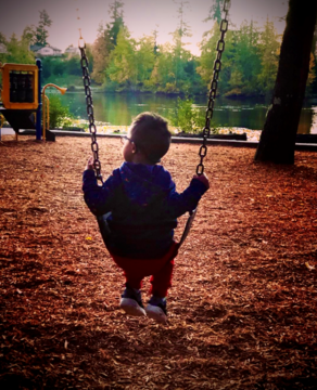 boy facing water on a swing