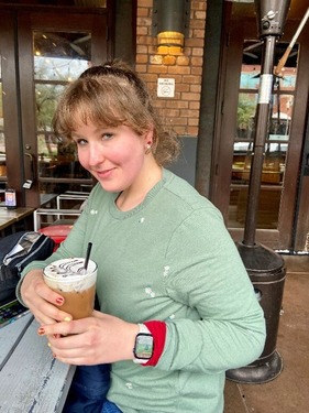 Photo of Support Specialist, Amanda Ernst, smiling and holding a decorative iced coffee beverage.