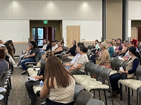 Dozens of people attend meeting in large room.