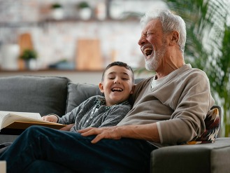Grandfather and grandson reading a book. Grandpa and grandson enjoying at home.
