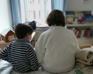 Child and grandmother sitting on a bed in a cozy room