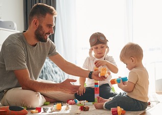Construction toys. Father is playing with two little boys on the floor
