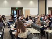 Group of people sitting in chairs in room in discussion and sharing.