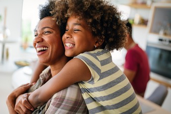 African american woman hugging her smiling teen daughter. 