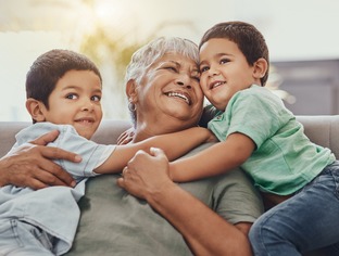 Children, hug and grandmother on a sofa, happy and smile, love and laugh while bonding on their home visit